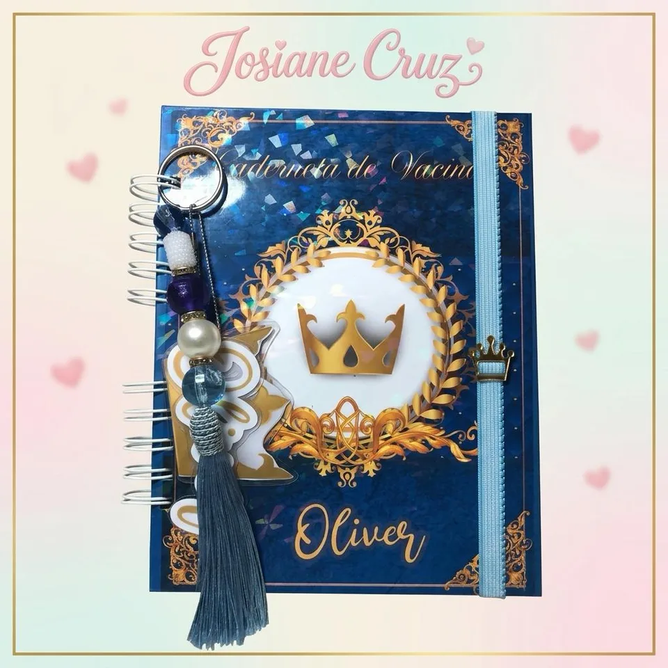 Caderneta de vacinas com capa azul, coroa dourada, nome personalizado e pingente.