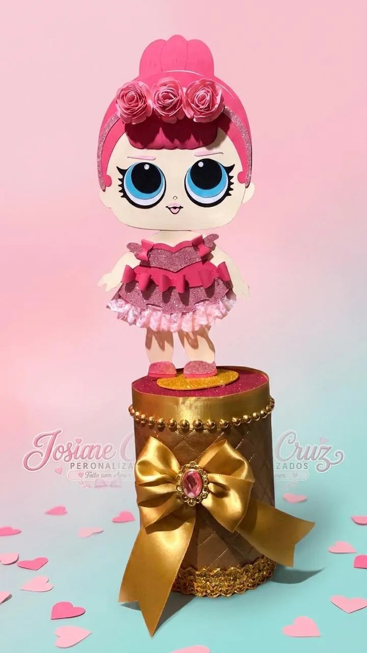 Centro de mesa com personagem de cabelo rosa sobre uma base dourada com laço.